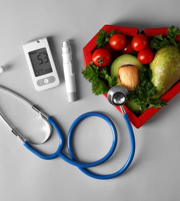 Digital-glucometer-with-lancet-pen-stethoscope-and-healthy-food-to-eat-for-diabetes-and-eyesight-on-grey-background.