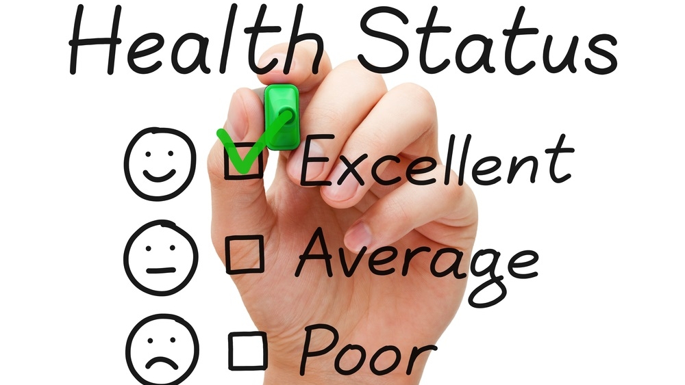 Hand putting check mark with green marker on excellent in Health Status evaluation form.