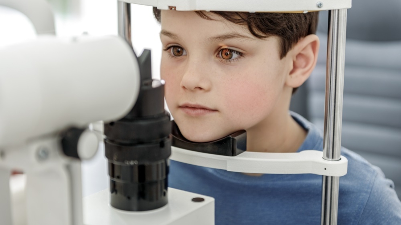 Attentive boy is looking in special apparatus, checking his eye sight.