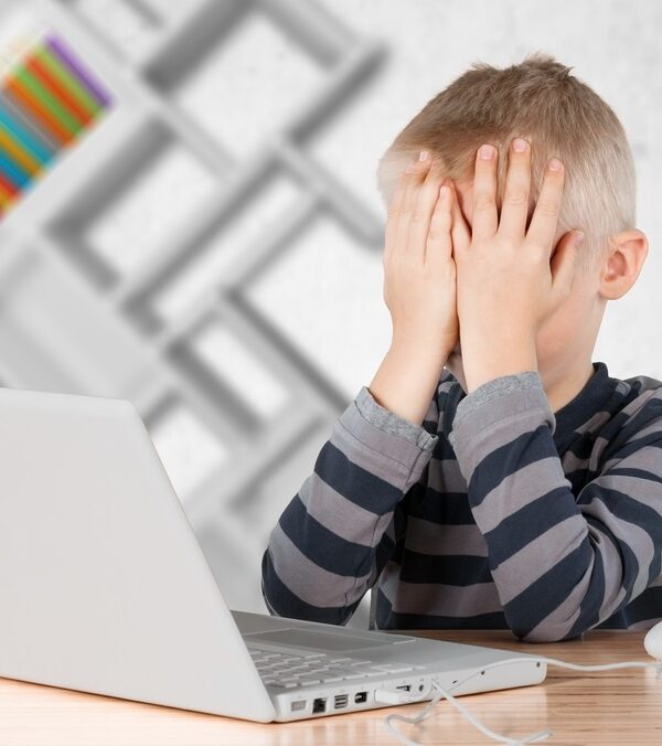 A Little Boy With His Hands Over His Eyes Sitting In Front Of His Computer