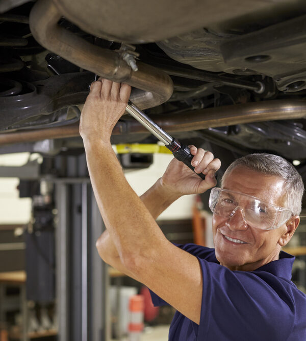 man working on underside of car wearing safety glasses