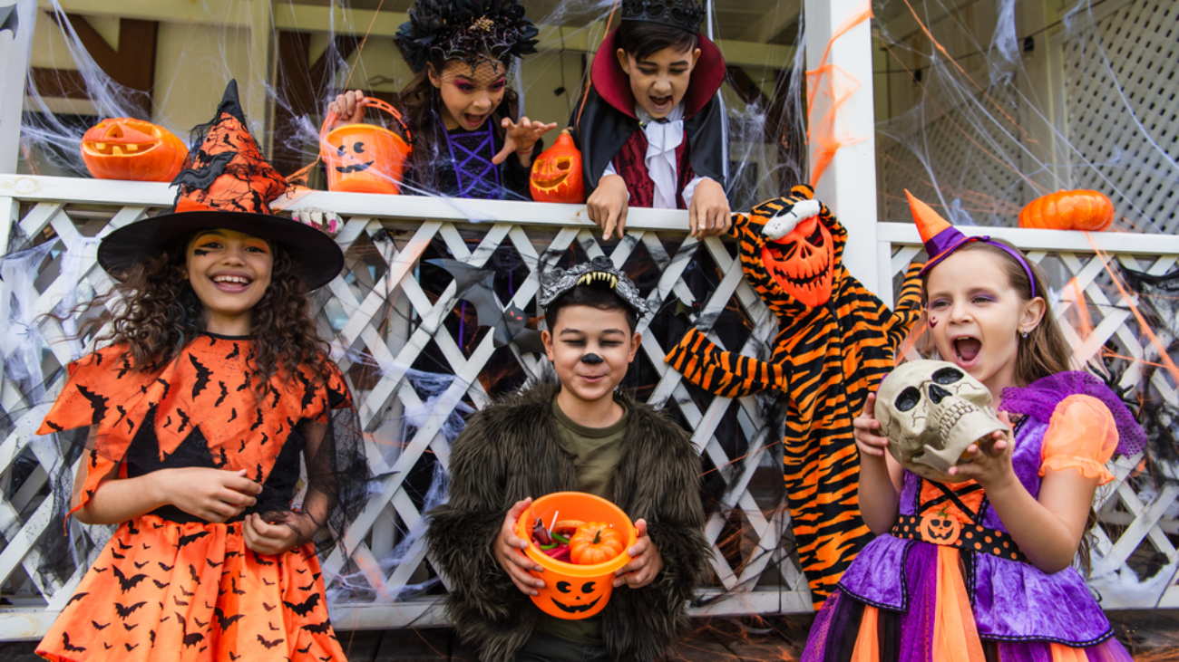A group of young children in Halloween costumes on a front porch, representing how to protect your vision this Halloween