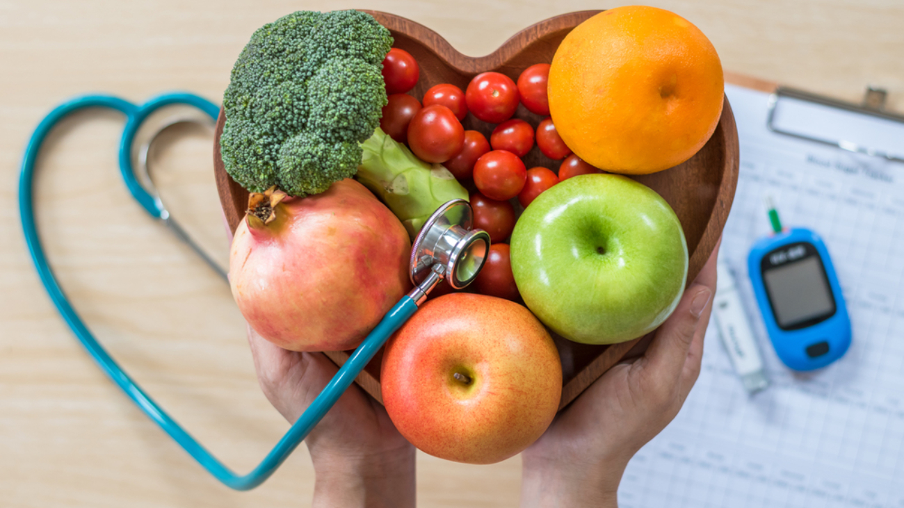 image of fruits and vegetables including apples oranges brocolli and tomatoes in a heart shaped bowl representing ways to reduce risk for diabetes