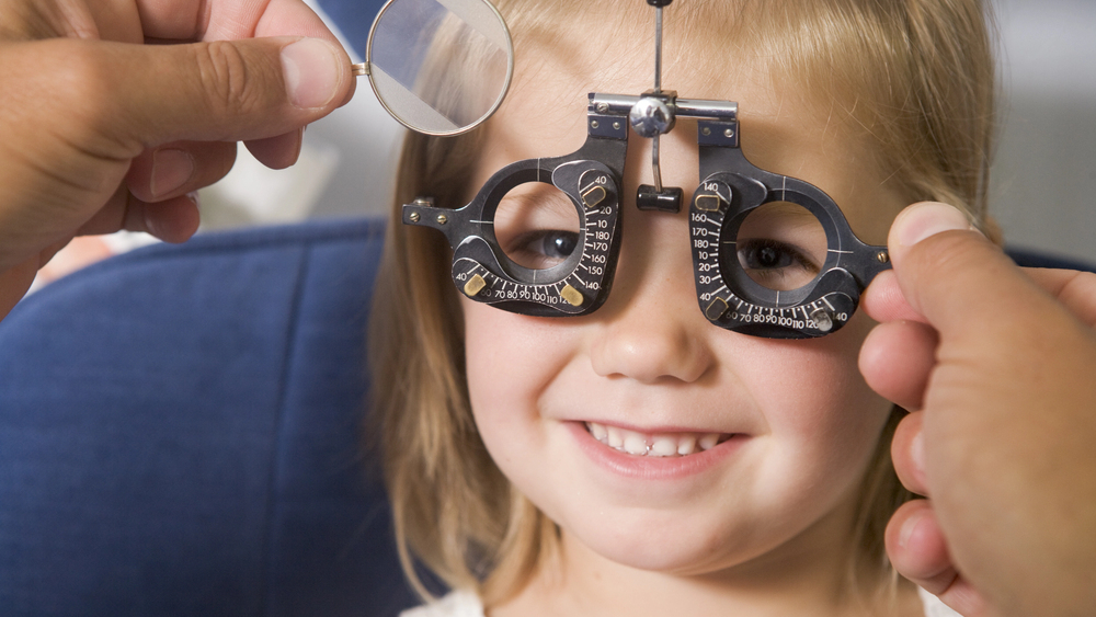 smiling young female child getting an eye exam Comprehensive Eye Exam