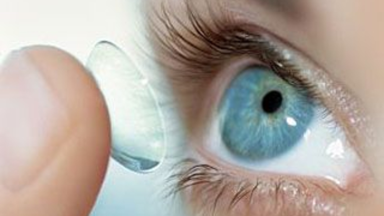 close up of bifocal contact lenses being placed in open eye via index finger