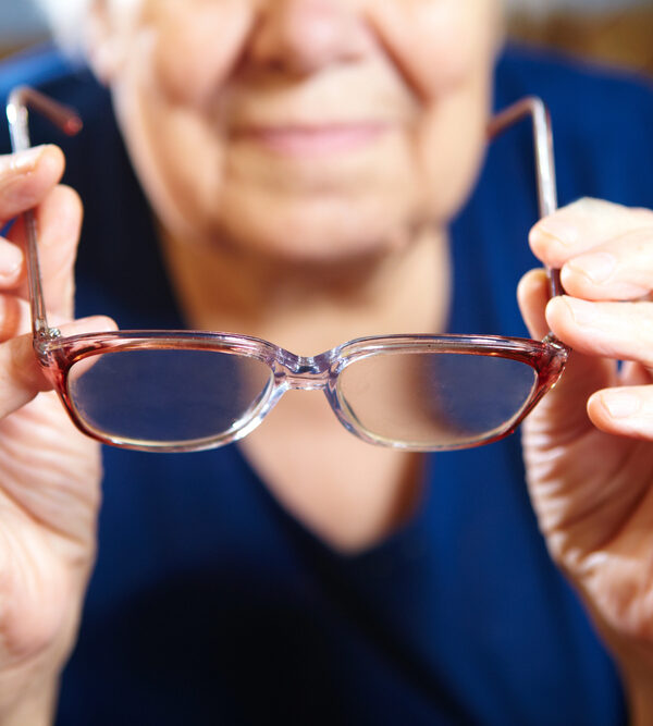 senior individual in blue shirt preparing to put on a pair of e-scoop eyewear glasses