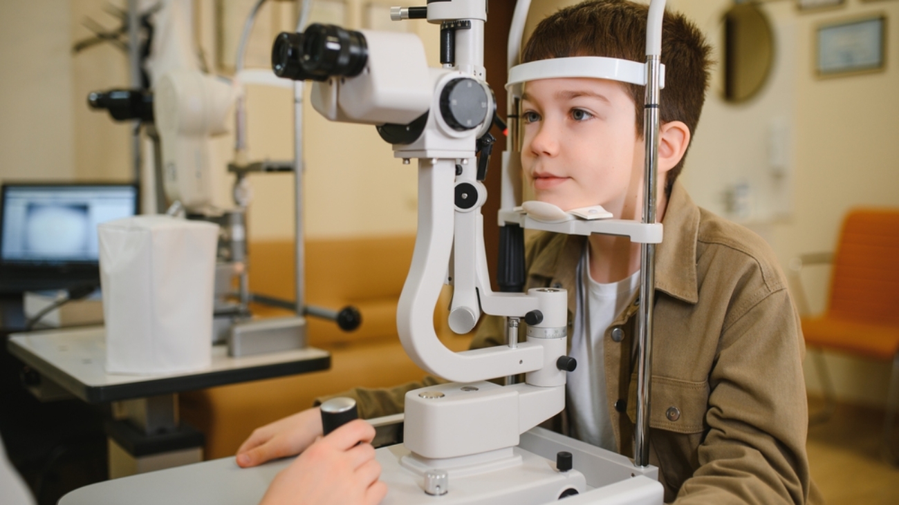 Boy undergoing eyesight examination with slit lamp biomicroscope in ophthalmology clinic back-to-school eye exam