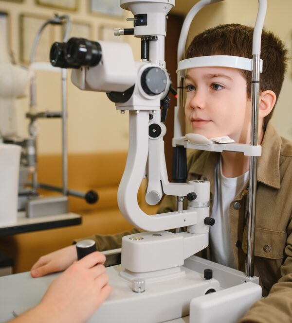 Boy undergoing eyesight examination with slit lamp biomicroscope in ophthalmology clinic back-to-school eye exam